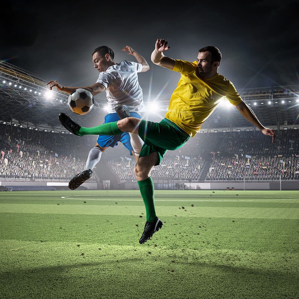 Three soccer players in a field with lights on.